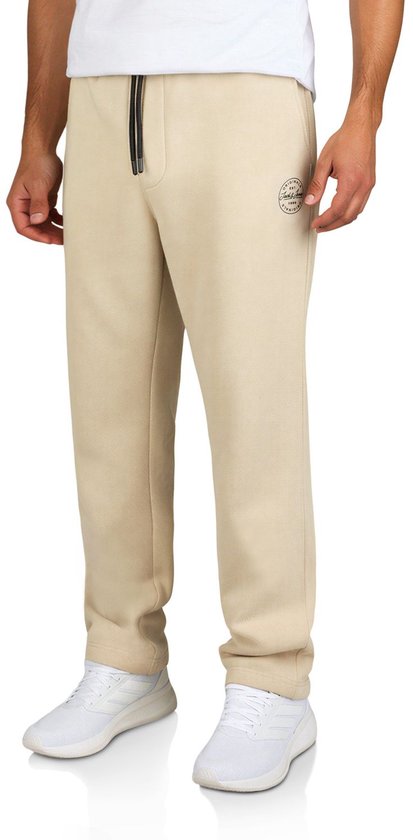 Model draagt beige Jack & Jones joggingbroek met zwart trekkoord en rond logopatch op het been.