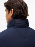 Donkerblauwe Tommy Hilfiger gewatteerde jas met merknaam op de kraag, gedragen door een man.
