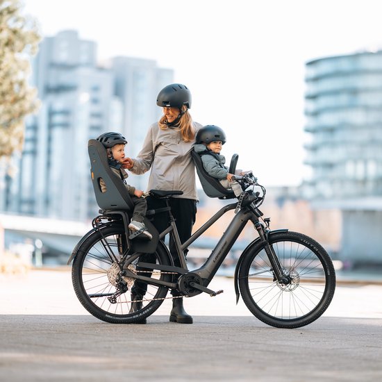 Vrouw met twee kinderen in Thule Yepp Nexxt 2 kinderzitjes op een zwarte Lapierre elektrische fiets in de stad.
