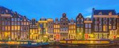 Fotobehang Amsterdamse grachtenhuizen met woonboten in het avondlicht 450 x 260 cm - € 239