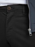 Sluiting van een zwarte chino met knoop en ritssluiting, met donkerblauw bomberjack.