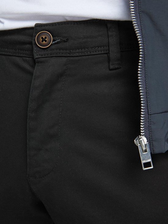 Sluiting van een zwarte chino met knoop en ritssluiting, met donkerblauw bomberjack.