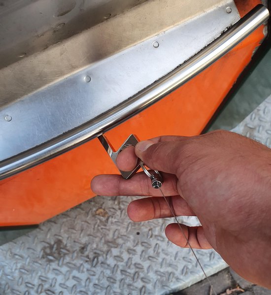 Zilverkleurige haaksleutel met sleutelring wordt gebruikt om een oranje en metalen bootrand aan te raken.