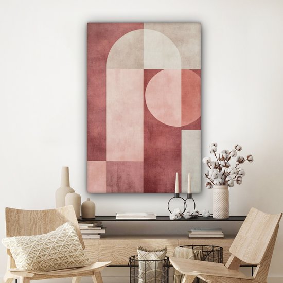 Peinture abstraite rose, beige et blanc avec des formes géométriques accrochée au-dessus d'un buffet avec décoration.