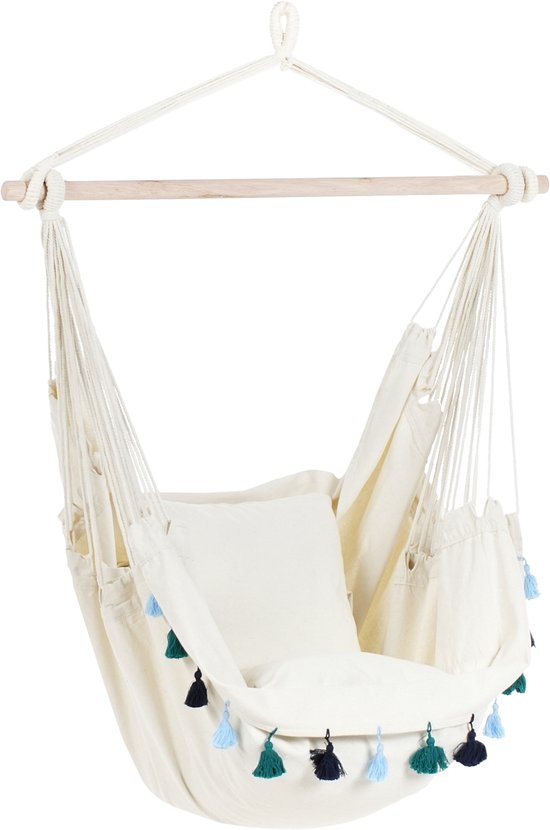 Beige hangstoel met een wit kussen, versierd met blauwe en groene kwastjes, met houten dwarsbalk.
