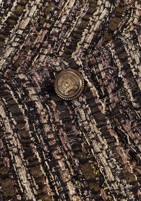 Fermeture d'un bouton détaillé en cuivre avec une image sur un tissu tweed noir, brun et doré.