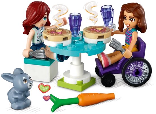 Figurines LEGO Friends à une table avec des crêpes, des verres et un lapin.