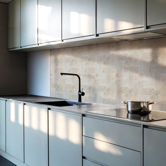 Moderne keuken met beige steenmozaïek muurtegels achter een zwarte kraan en aanrecht.