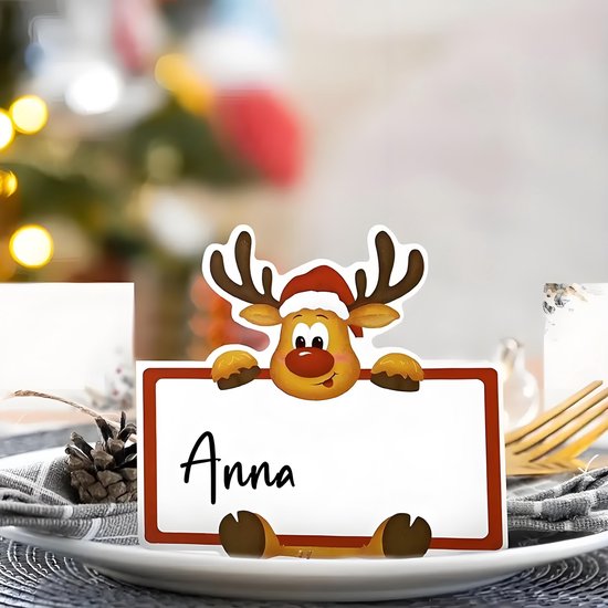 Rendier naamkaartje met de naam 'Anna', op een bord geplaatst met achtergrond van kerstdecoratie.
