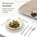 Een gedekte tafel met een salade en bestek van de Deleca Amor collectie, met een glas rode wijn.