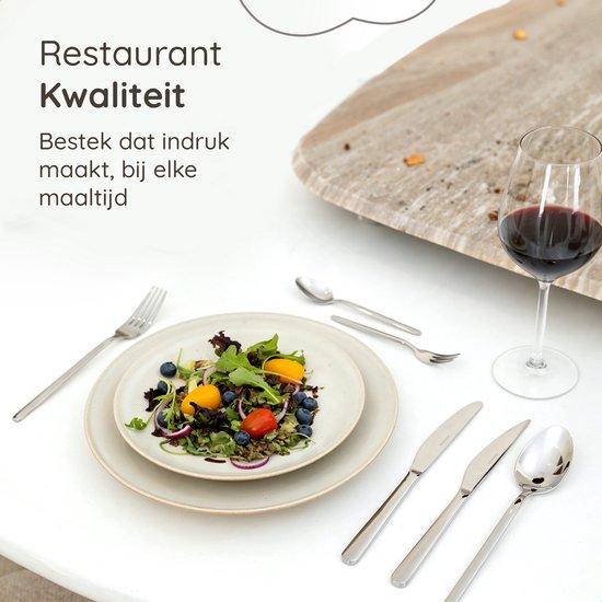 Een gedekte tafel met een salade en bestek van de Deleca Amor collectie, met een glas rode wijn.