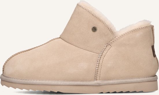Zijzicht van een beige suède pantoffel met teddy voering en een bruin Warmbat label.