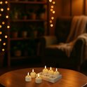 Tafel met zes witte led-kaarsen in een houder, zacht verlicht door het kerstverlichting op de achtergrond.