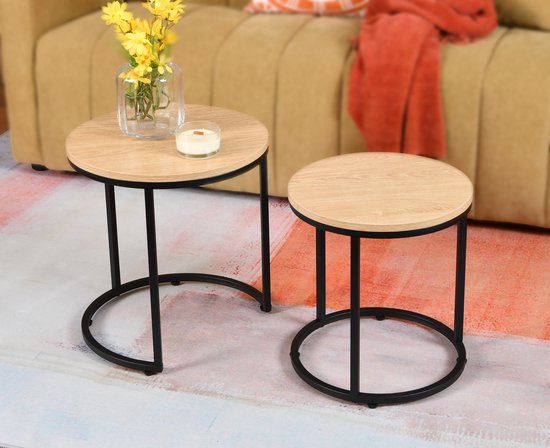 Deux tables d'appoint rondes avec plateau aspect chêne et cadre en métal noir, à côté d'un canapé.