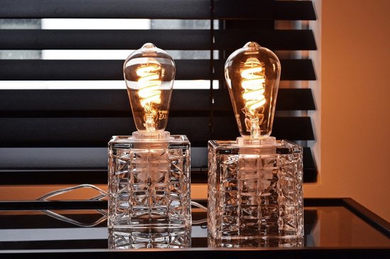 Twee rustieke gloeilampen met gedraaide LED-draden, staand op glazen kubus lampvoeten.