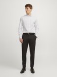 Man met wit overhemd en zwarte broek, met zwarte riem.