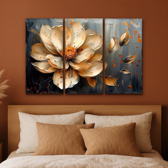 Une peinture triptyque d'une fleur abstraite dorée avec des accents orange sur un fond gris foncé, placée au-dessus d'un lit.