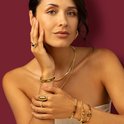 Vrouw met gouden ring met tijgeroog edelsteen en gouden armbanden.