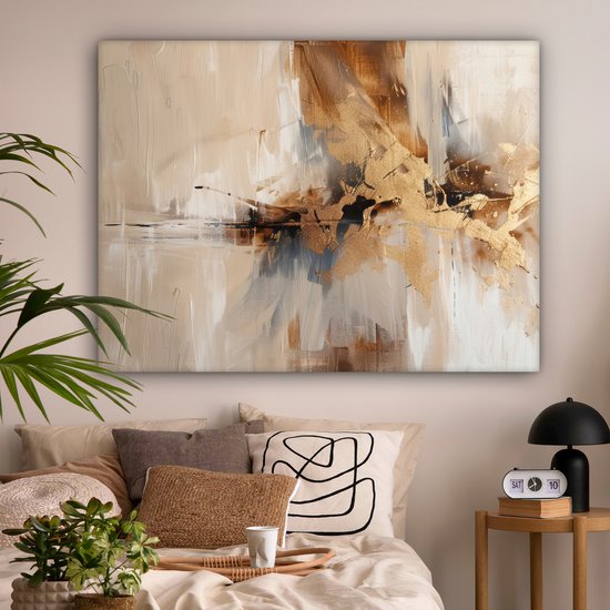 Een abstract doek in bruin- en beigetinten met gouden accenten, hangend boven een bed met beige kussens.