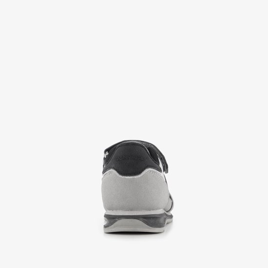 Achterkant van een grijze sneaker met zwarte en grijze accenten en klittenbandsluiting.