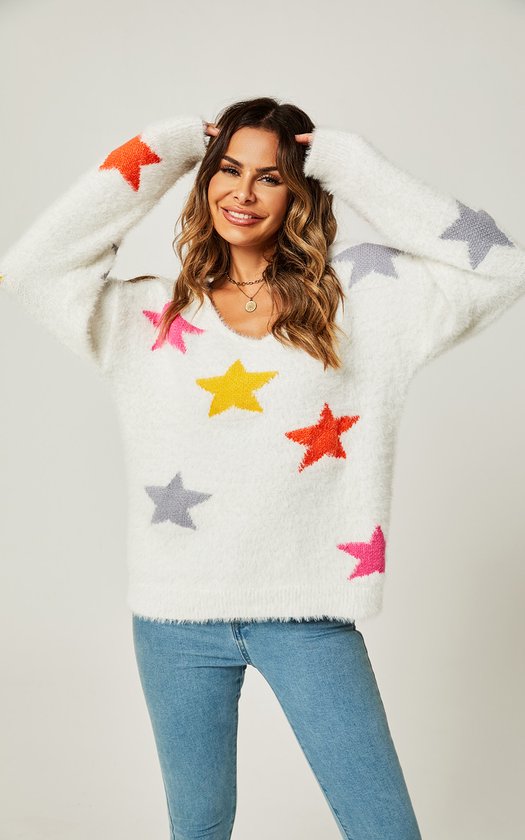 Model draagt witte, pluizige trui met veelkleurige sterrenprint en V-hals. Blauwe jeans.