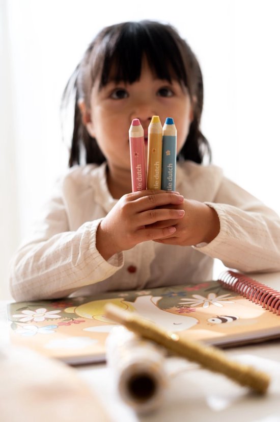 Een meisje houdt drie gekleurde Little Dutch potloden vast voor een kleurboek met een konijn.