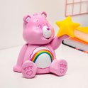 Veilleuse Cheer Bear rose avec un arc-en-ciel et une étoile jaune, sur un bureau.