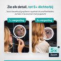 Vrouw brengt make-up aan in een spiegel met 1x vergroting en een close-up van haar oog met 5x vergroting.