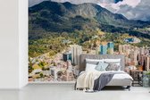 Behang - Fotobehang De zon schijnt op het gebergte achter de Colombiaanse hoofdstad Bogota - Breedte 600 cm x hoogte 400 cm