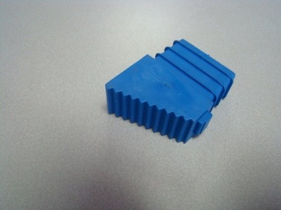 Blauw trapvoetje met groeven op een grijze ondergrond.