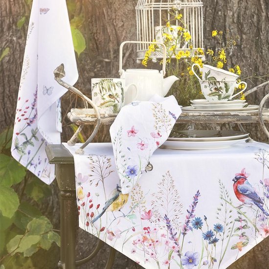 Wit tafellaken met vogels en bloemen, met mokken en theepot buiten.