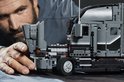 Man bouwt aan een grijze LEGO Technic Mack Anthem truck. Detail van de cabine.