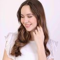 Een jonge vrouw met lang bruin haar draagt een zilverkleurige ring met zirkonia.