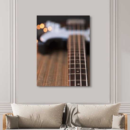 Une guitare basse repose sur le sol Toile 120x160 cm - Tirage photo sur toile (Décoration murale salon / chambre) XXL / Groot format!