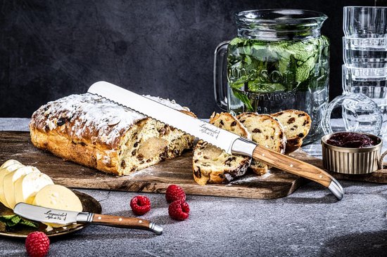 Glaceerd brood met rozijnen en amandelen, gesneden, met een broodmes met olijfhouten handvat en fruit.