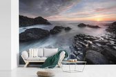 Behang - Fotobehang Zonsondergang en stromend water over de Giants Causeway in Noord-Ierland - Breedte 420 cm x hoogte 280 cm