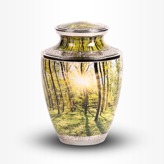Een urn met een afbeelding van een groen bos met bomen en een opkomende zon. De randen zijn van metaal.