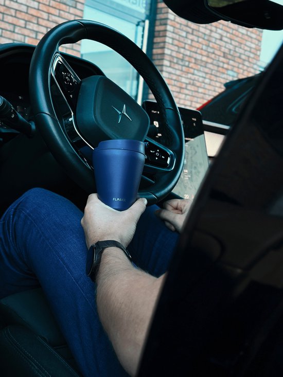 Hand die een blauwe FLASKE beker vasthoudt in een auto.