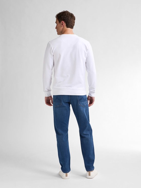Achteraanzicht van een model in een wit shirt en blauwe tapered fit jeans.