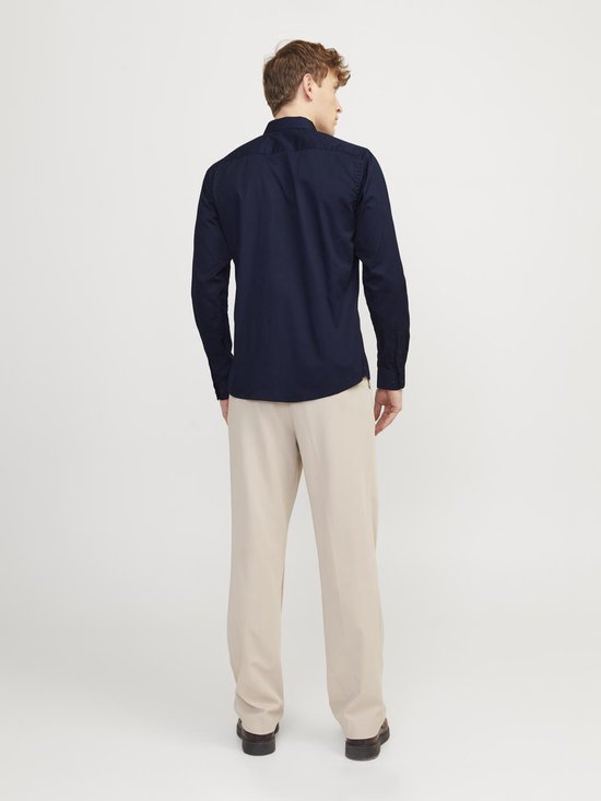 Man met marineblauw overhemd en beige broek, staand, achterkant.