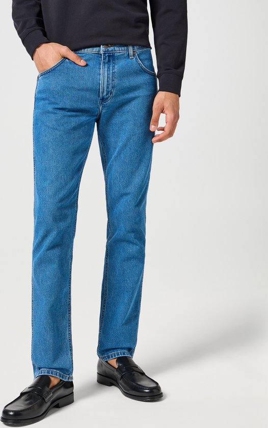 Model draagt Wrangler Greensboro jeans in 'Raindrop' wassing. De broek is blauw.