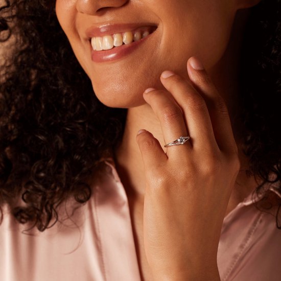 Een vrouw met een donkere huid draagt een zilverkleurige ring met zirkonia.