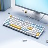 Clavier mécanique blanc avec touches bleues et jaunes, connecté à un ordinateur.