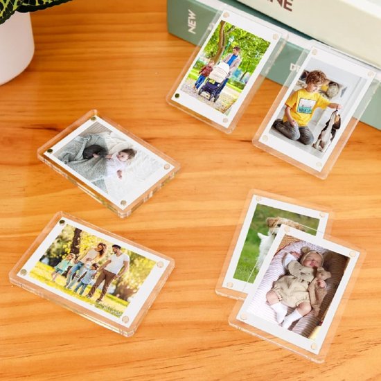 Vijf heldere magnetische fotolijstjes met foto's van gezinnen en kinderen op een houten tafel.