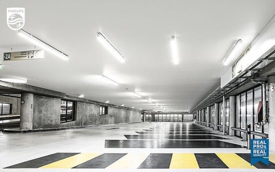 Verlichte parkeergarage met Philips lampen, betonnen pilaren en gele markeringen.