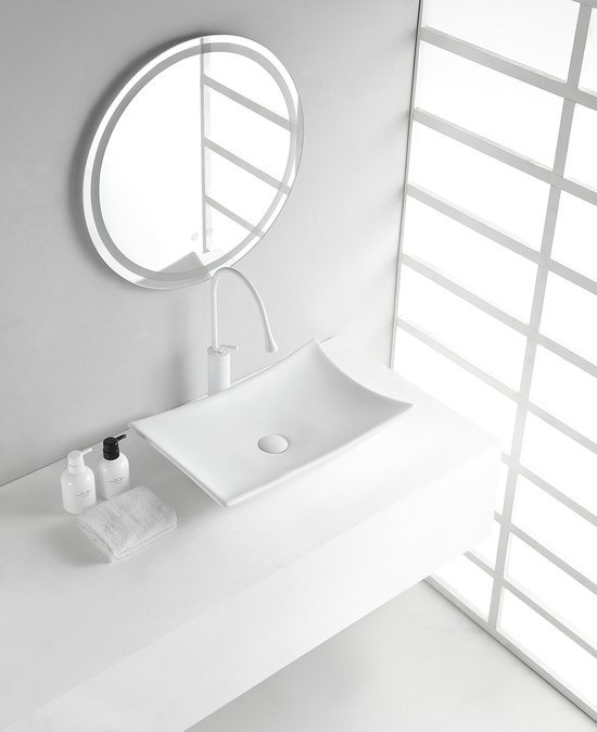 Witte opzet wastafel met gebogen randen, met een witte kraan en ronde spiegel.