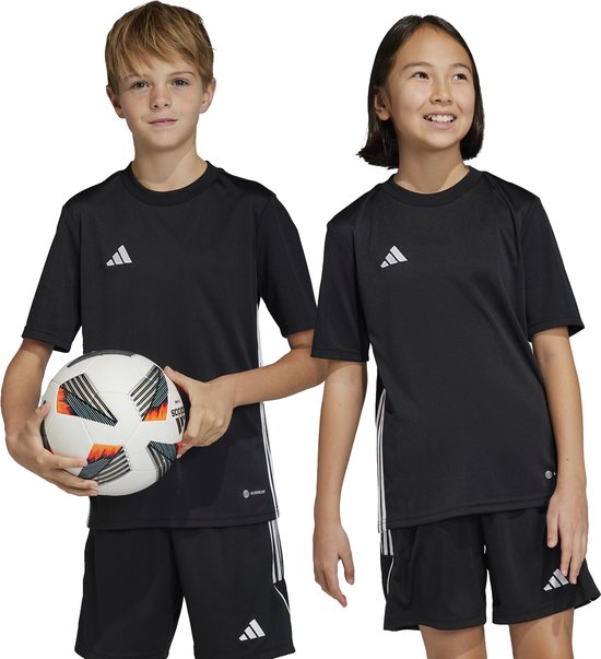 Jongen met voetbal en meisje, beide in zwarte Adidas sportshirts met witte strepen.
