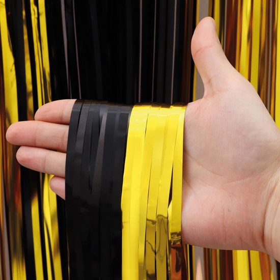 Hand die een bundel zwart gouden glittergordijn vasthoudt, tegen de glanzende achtergrond.