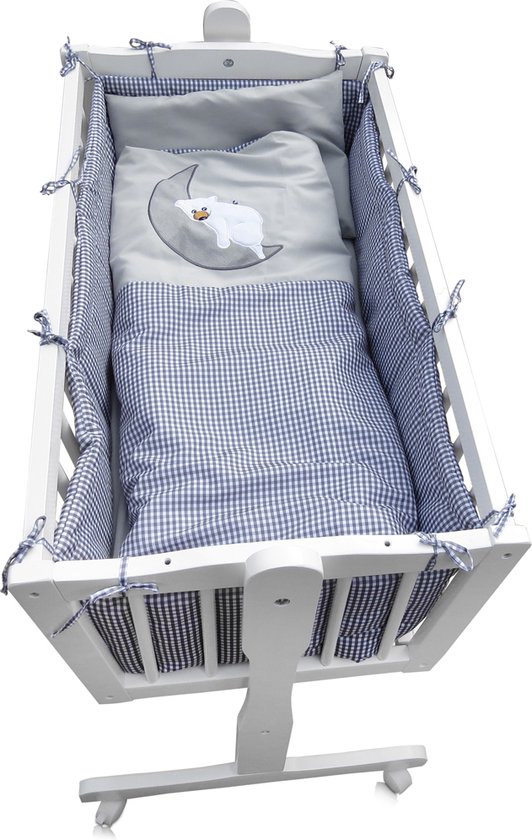 Witte wieg met blauw-wit geblokte bekleding en een dekbed met een maan en schaap motief.