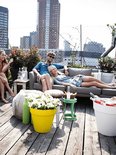 Riant terras met mensen op een grijze bank. Een okergele bloempot met witte bloemen staat op de voorgrond.